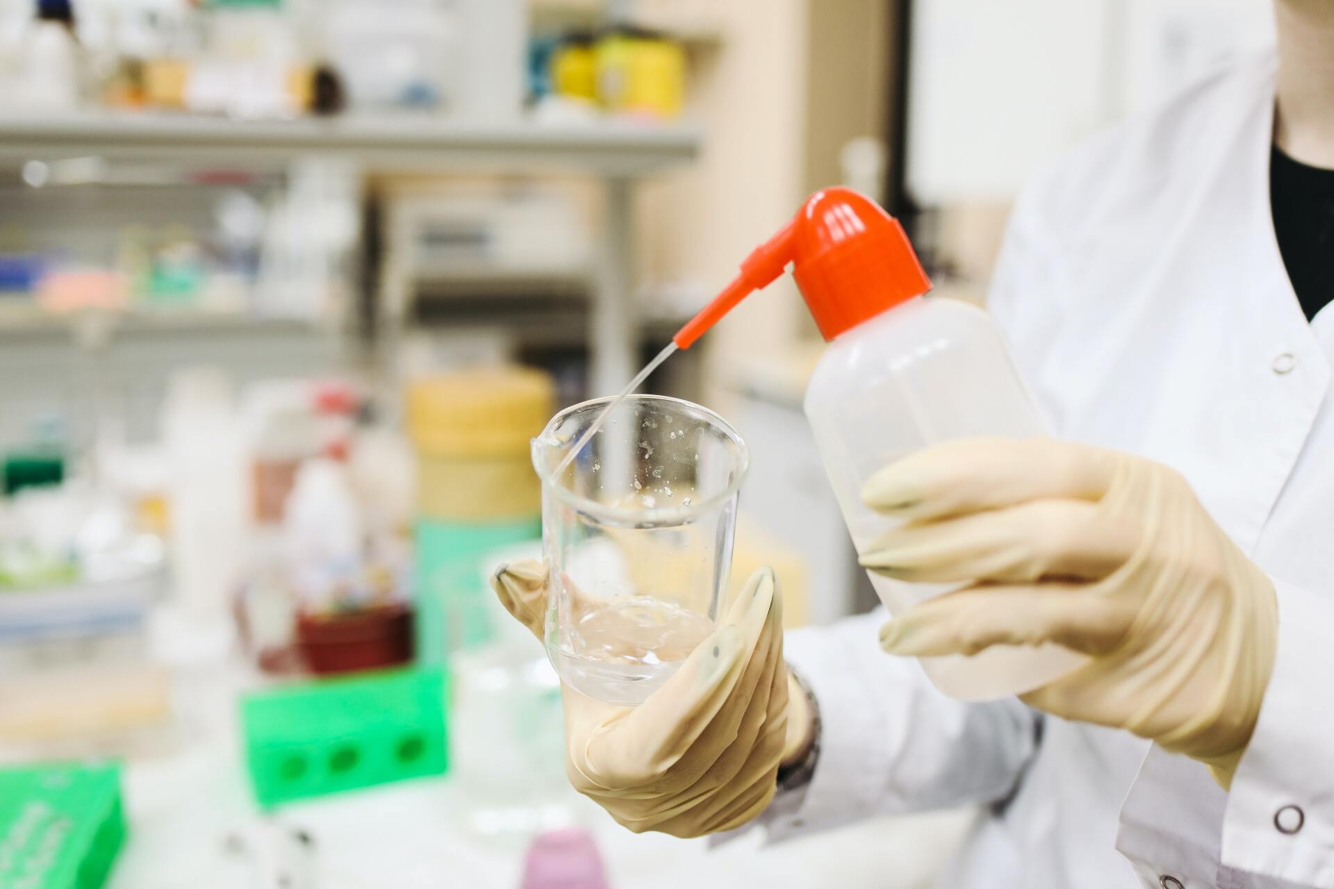 A scientist is pouring liquid into a beaker in a laboratory.