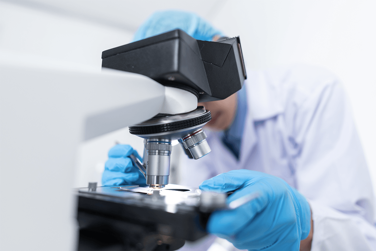 lab worker looking into microscope