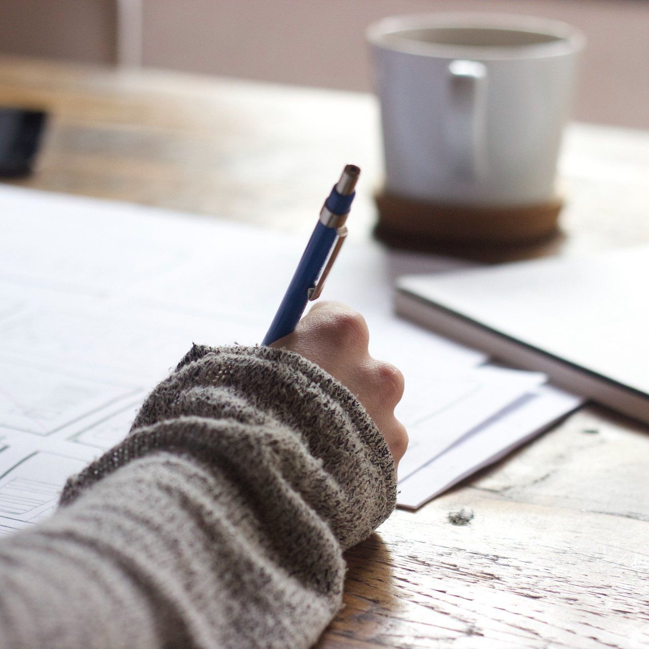 A person is writing on a piece of paper with a blue pen
