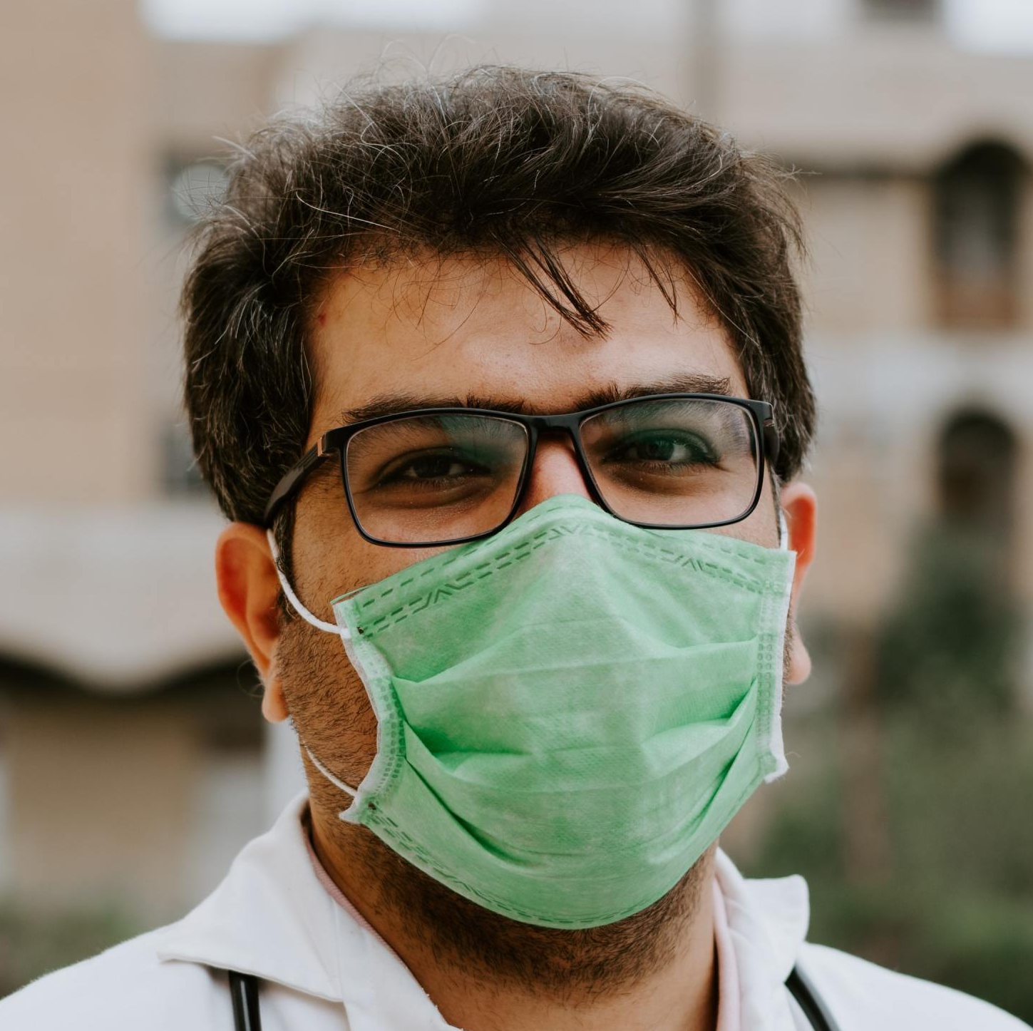 A man wearing glasses and a green face mask