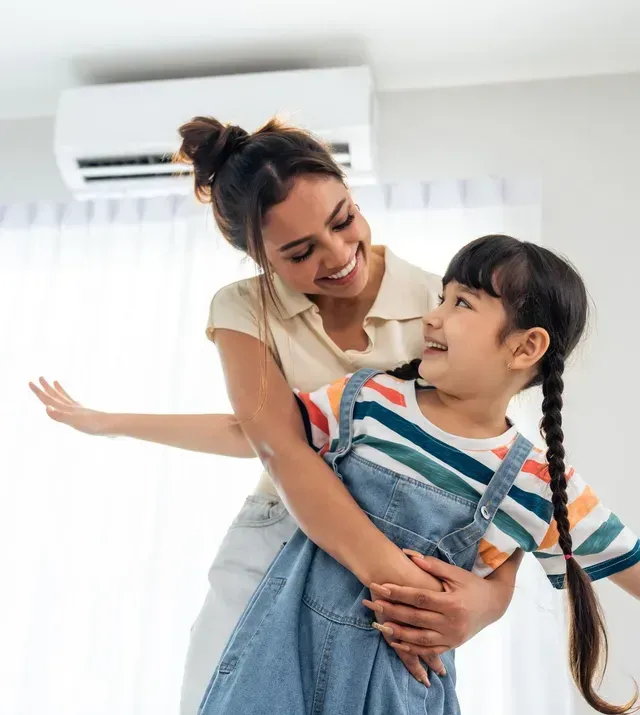 A woman is holding a little girl in her arms in a living room.