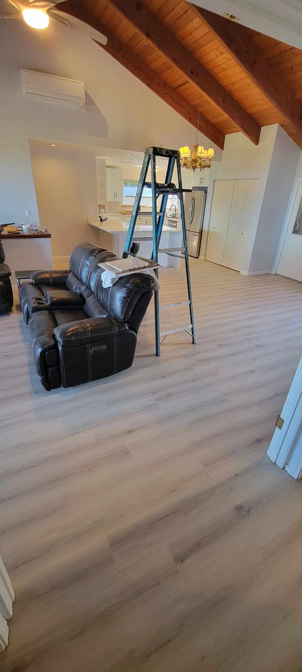 Loft room with black leather chair, ladder, and slanted wooden ceiling in a bright white interior