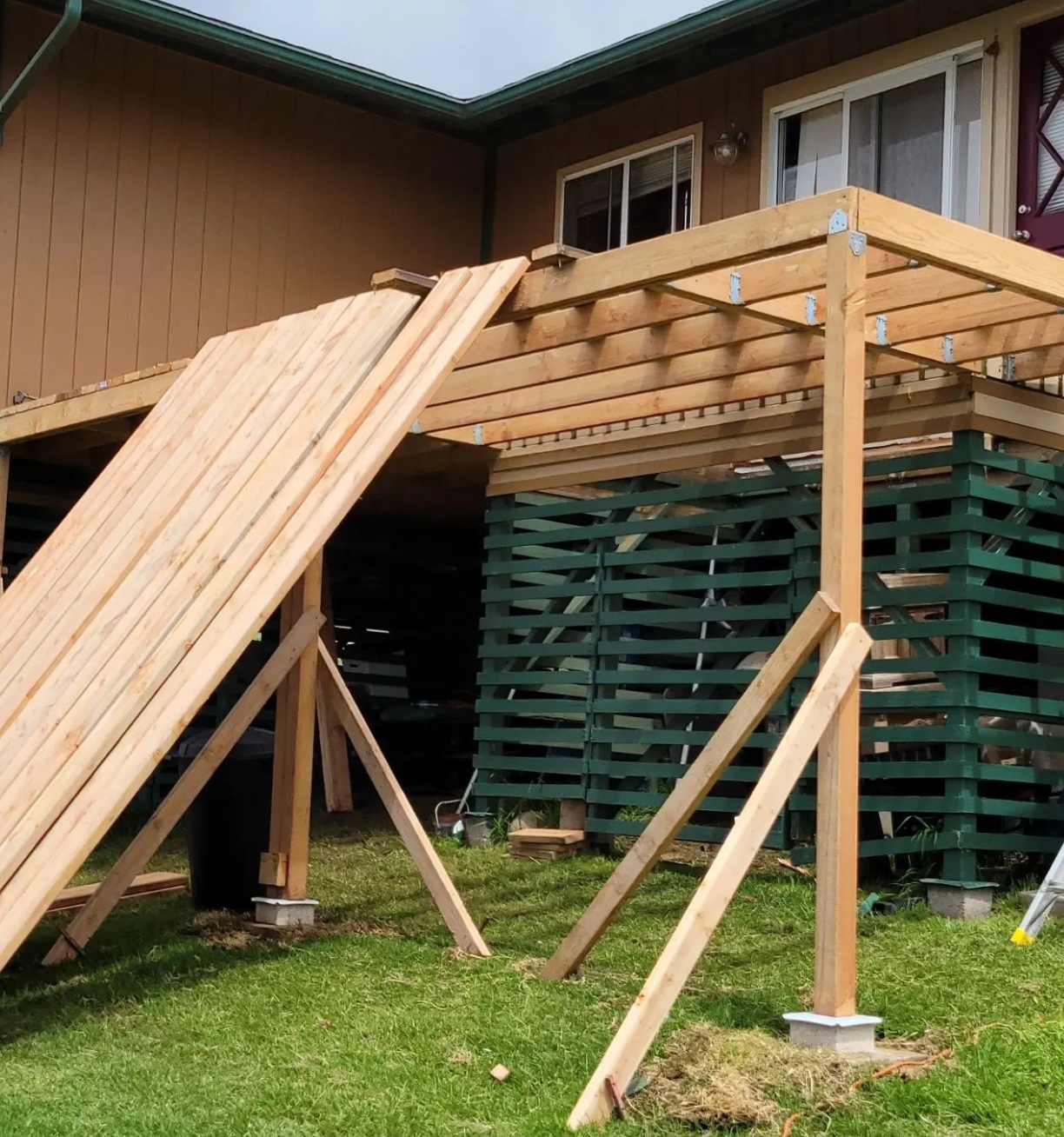Wooden ramp and deck under construction beside a house, with green lattice skirting and support posts.