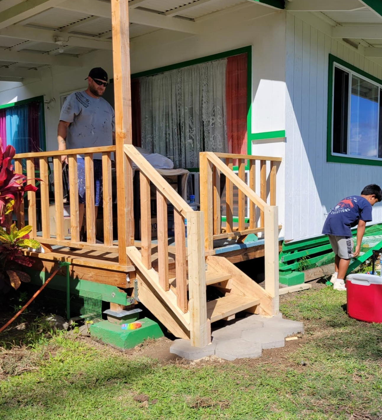 Two workers building a small wooden porch with steps on a white house