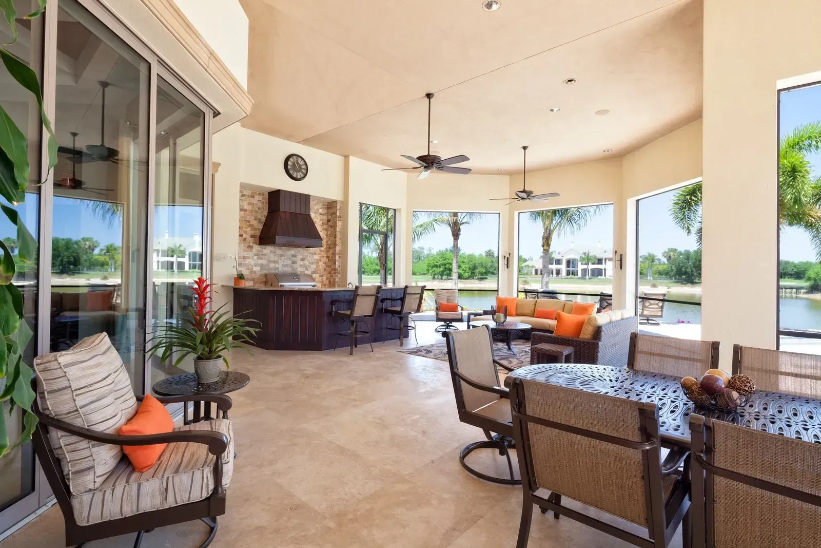 Spacious covered patio with wicker seating, a stone fireplace, and open views of the outdoors.
