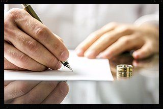 A man is writing on a piece of paper with a pen.