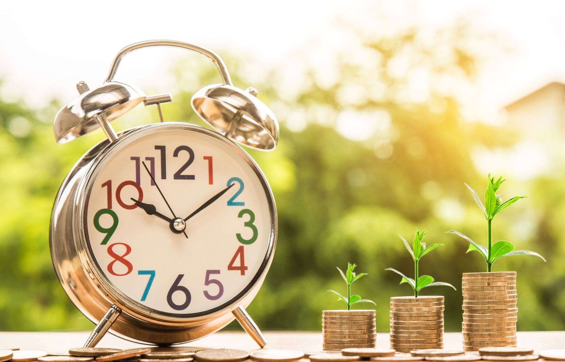 Gold alarm clock with stacked coins and growing plants