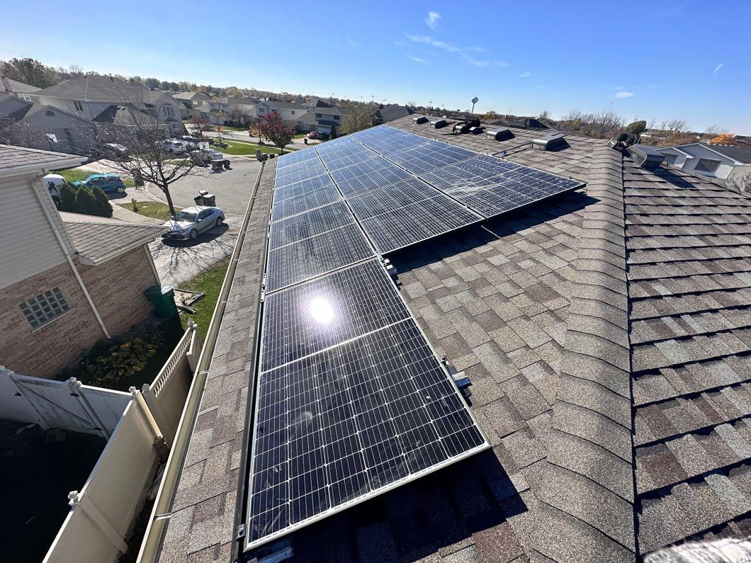 Solar panels installed on a shingled residential rooftop on a sunny day.