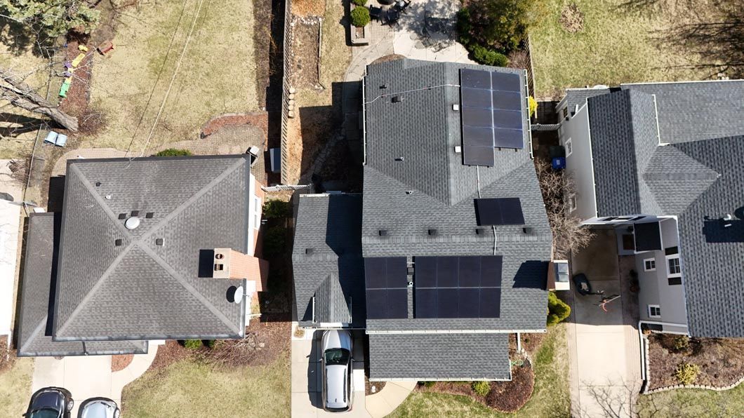 Overhead view of homes; the center one has solar panels on its roof.