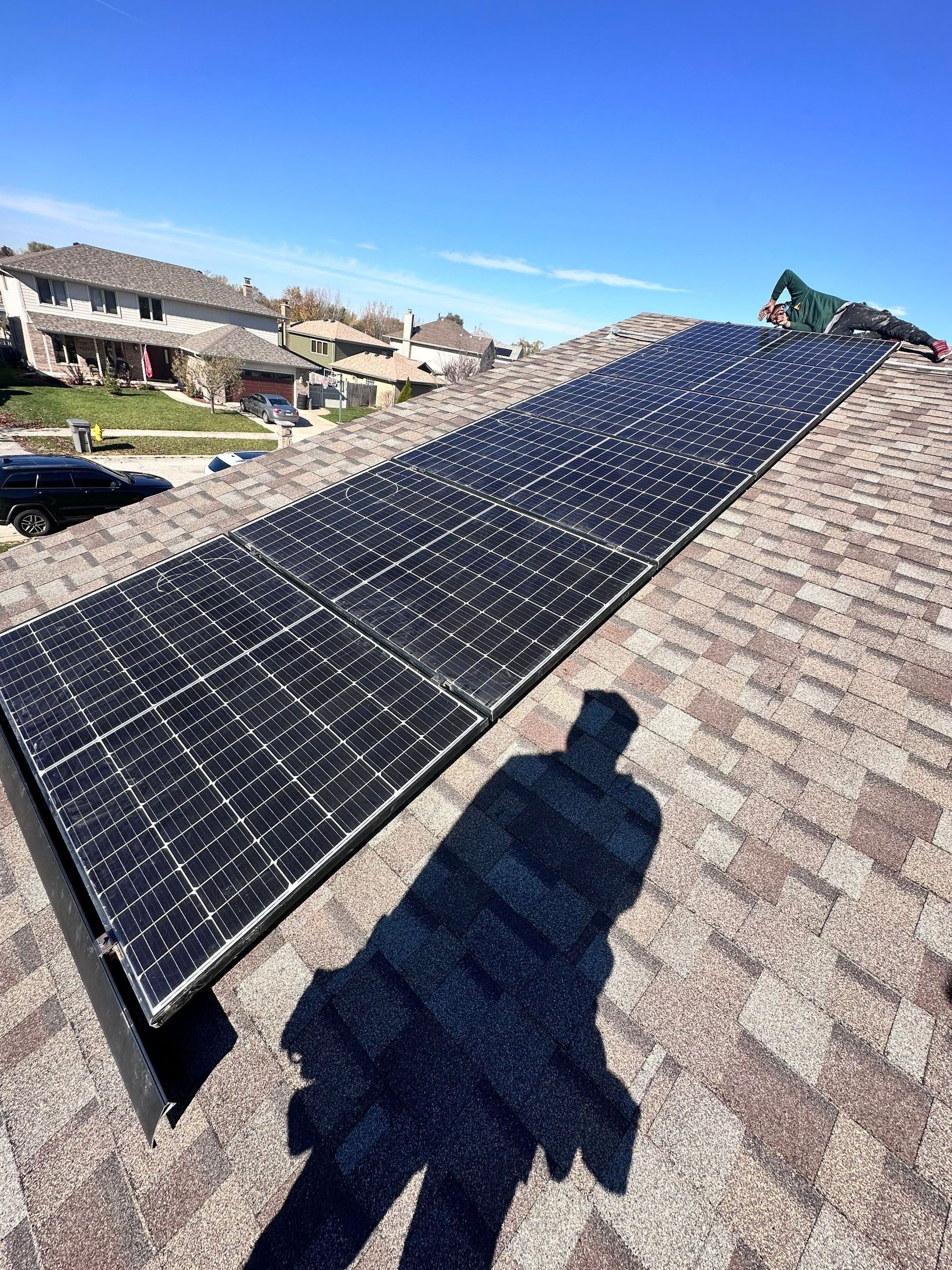 Solar panels installed on a residential roof under a bright blue sky.