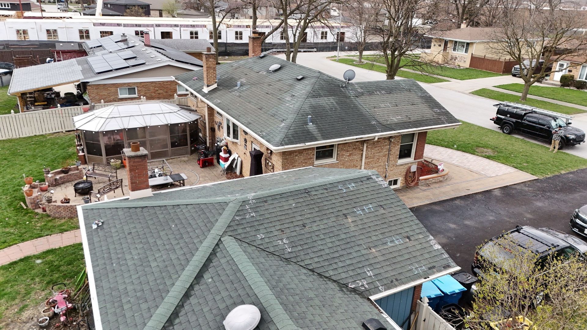 Overhead view of houses with green roofs and a brick exterior in a suburban neighborhood.