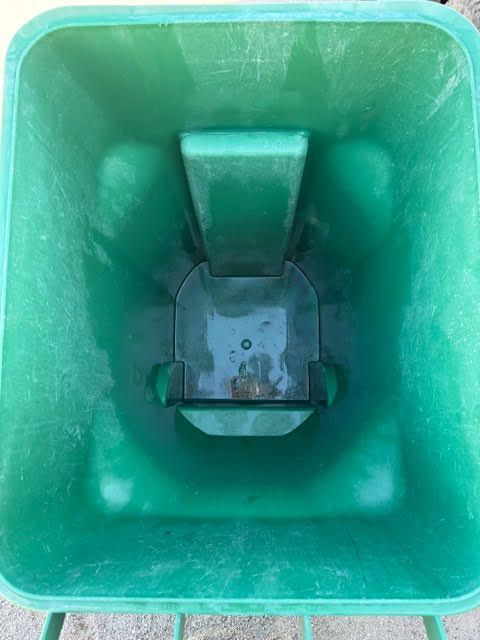 Inside a green plastic trash bin with a central divider and empty bottom.