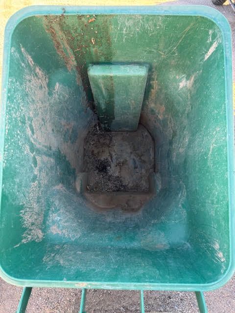 Inside a green plastic bin with a dirty bottom and water stains, viewed from above