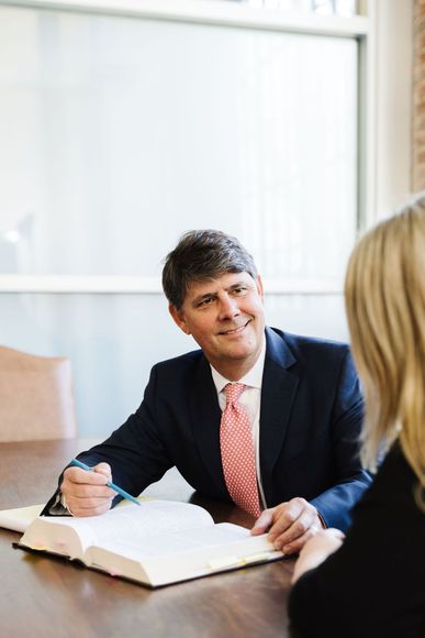 Harlan F. Winn, III in a suit and tie is sitting at a table talking to a woman.