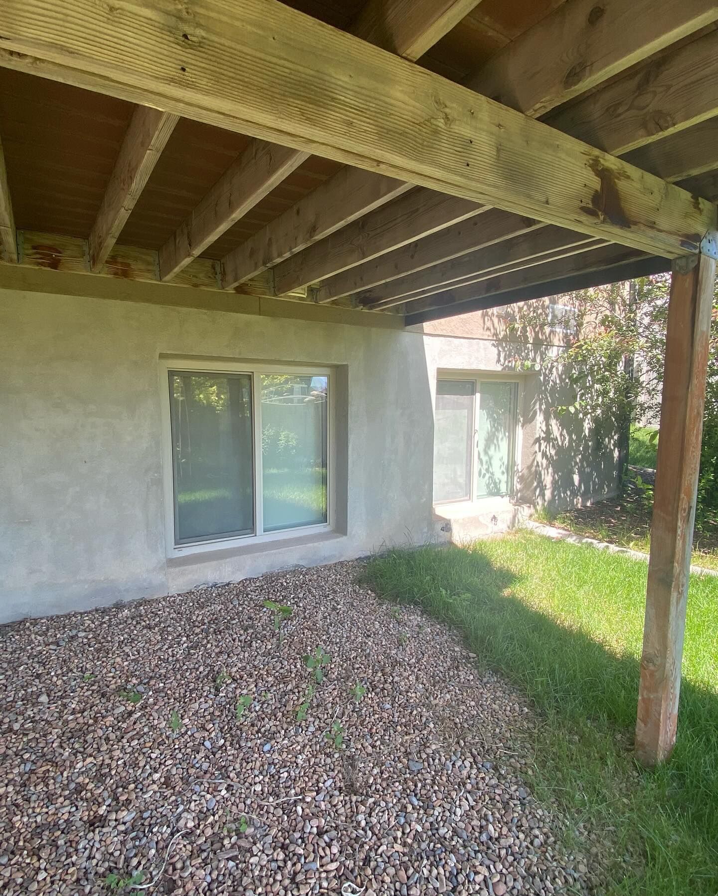 A house with a large window and a wooden deck underneath it.