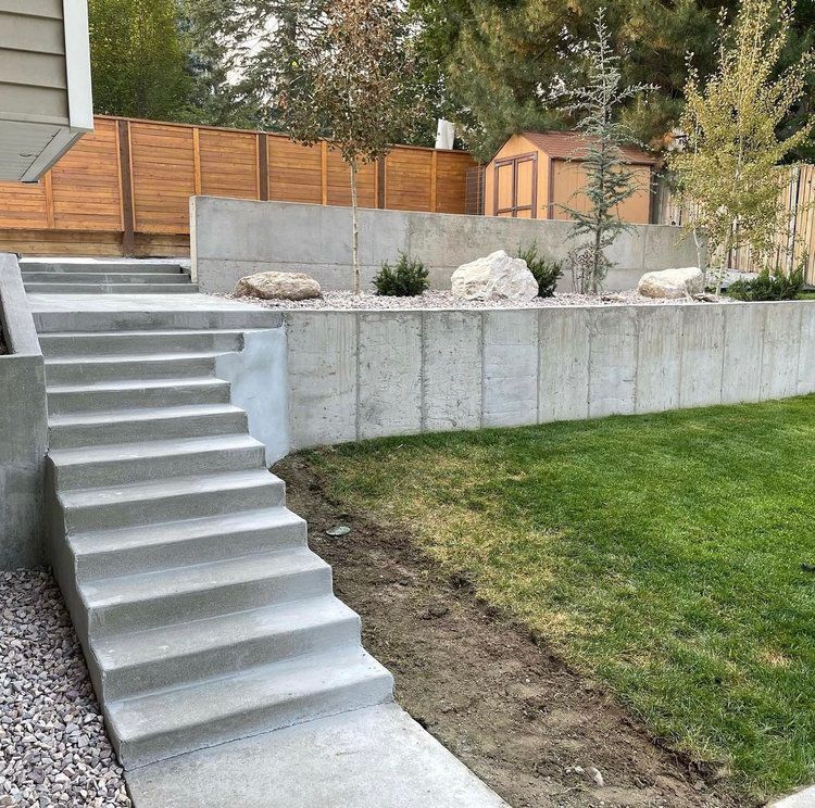 A set of concrete stairs leading up to a concrete wall in a backyard.