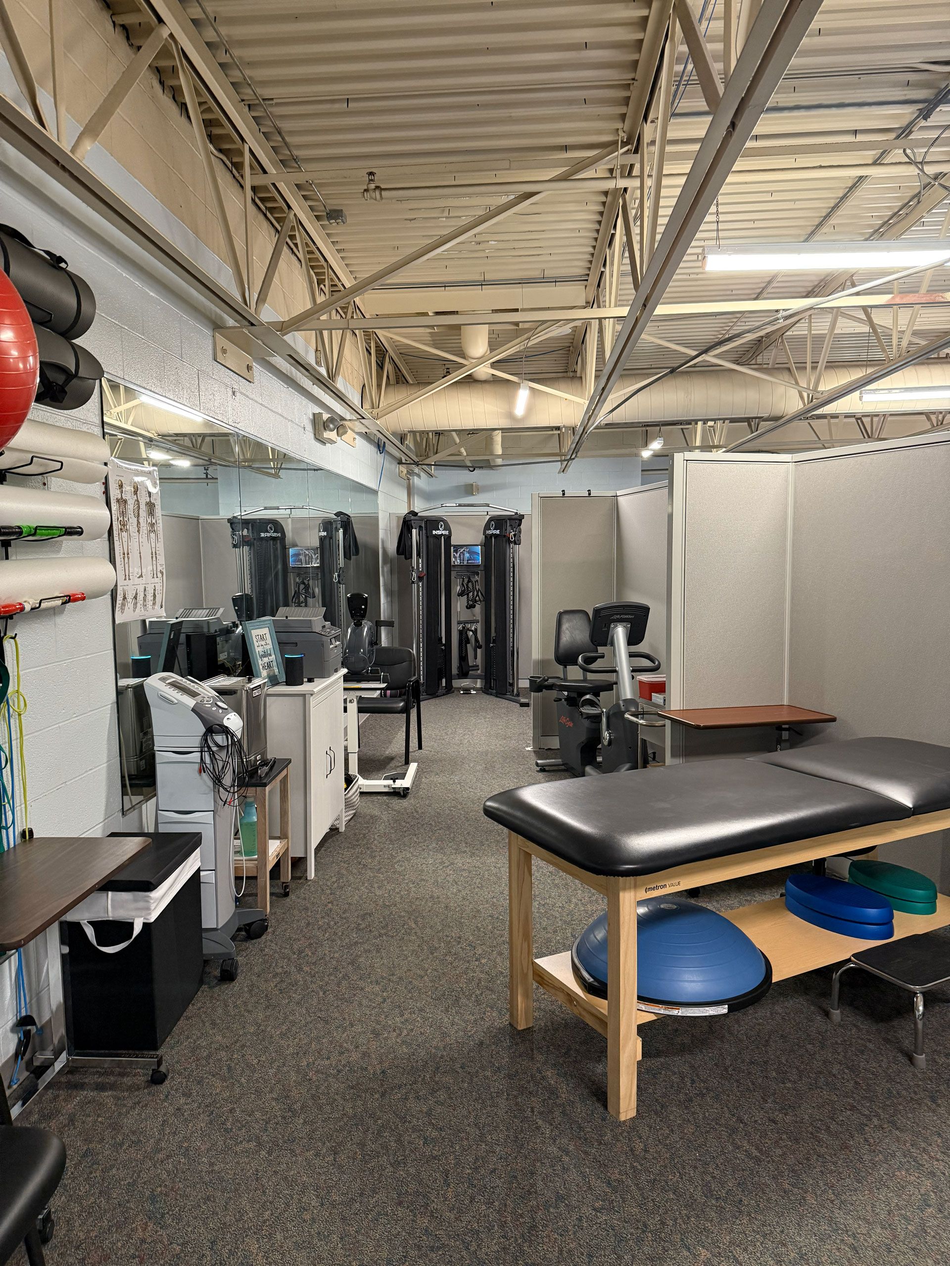 Physical therapy clinic interior with equipment, therapy table, and exercise balls.