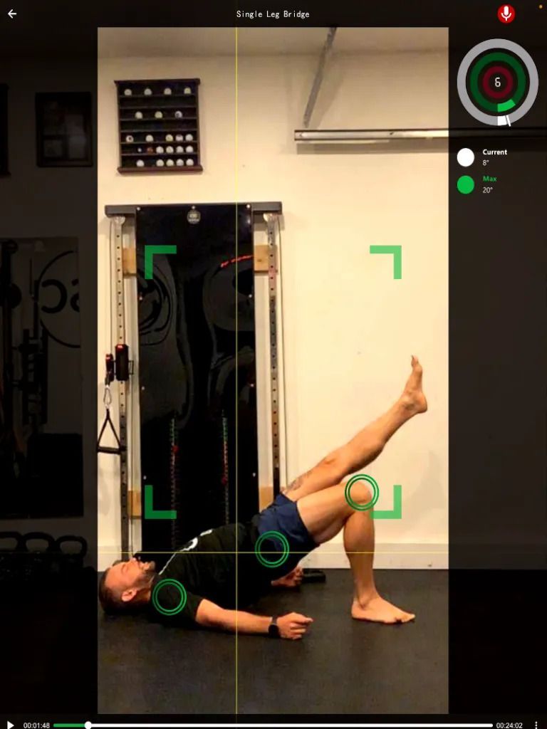 Man performing a single leg glute bridge exercise in a gym. Body is measured with green tracking markers.