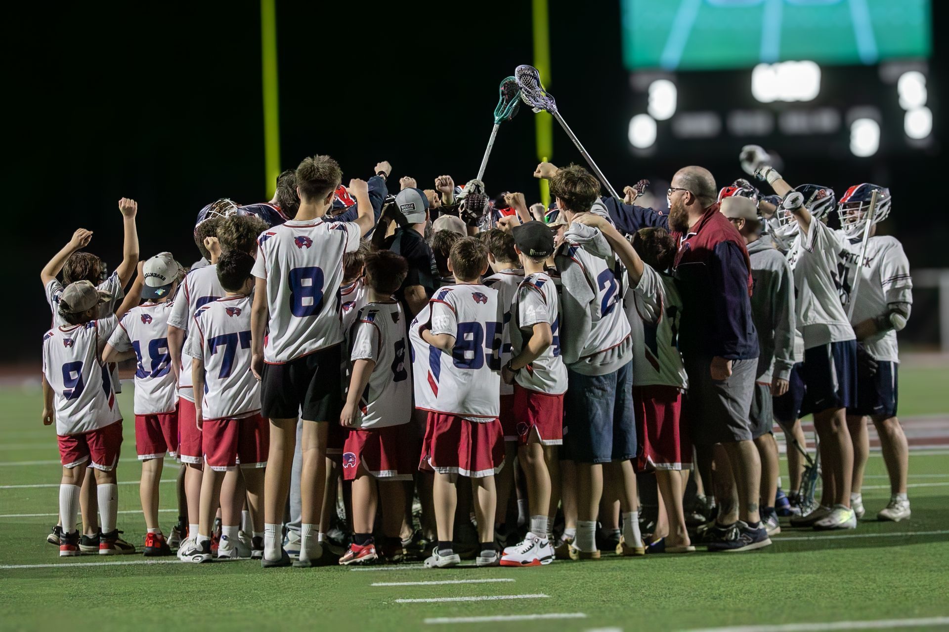 Lacrosse team huddles on a field