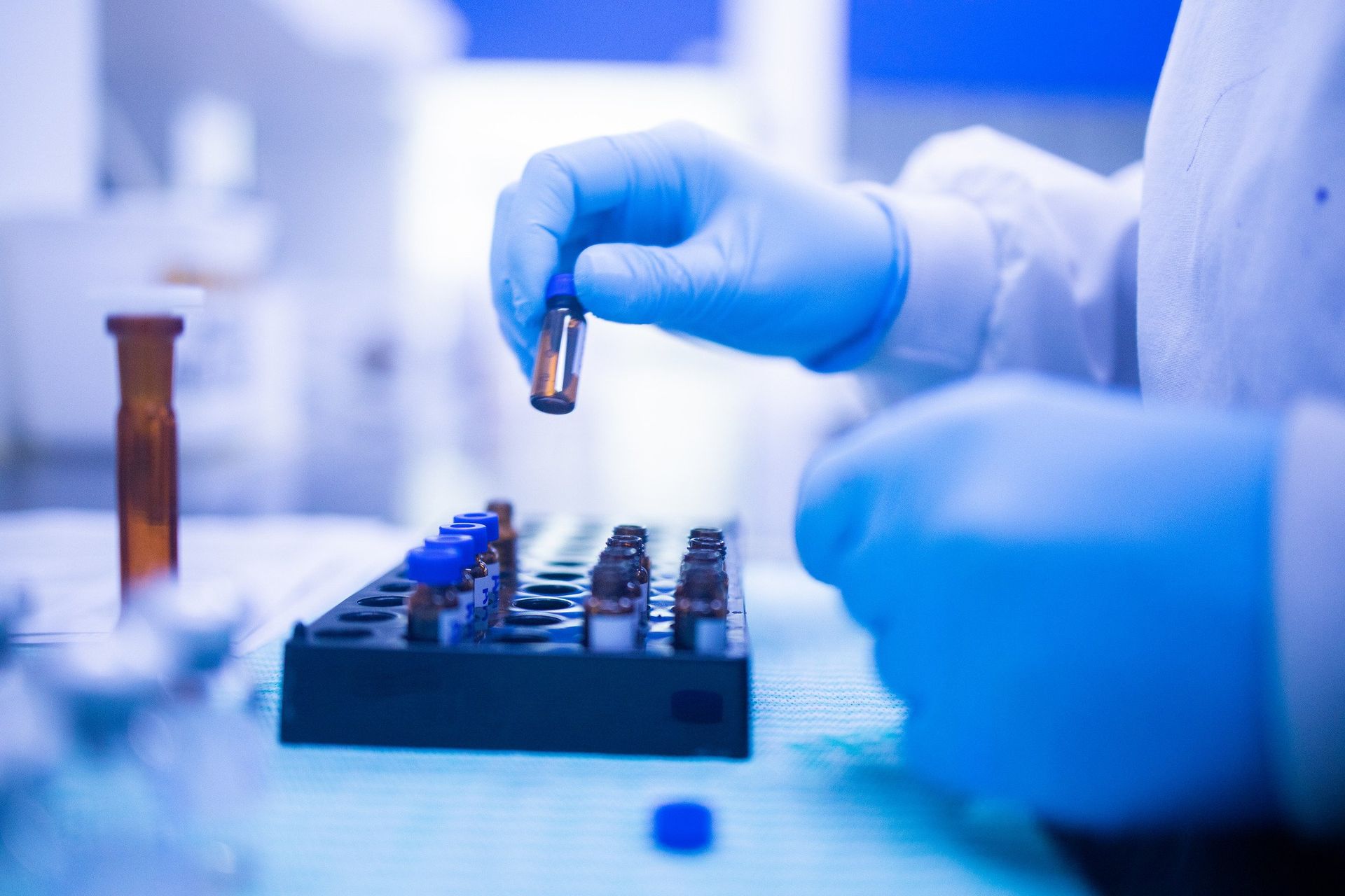 A person wearing blue gloves is holding a bottle in a laboratory