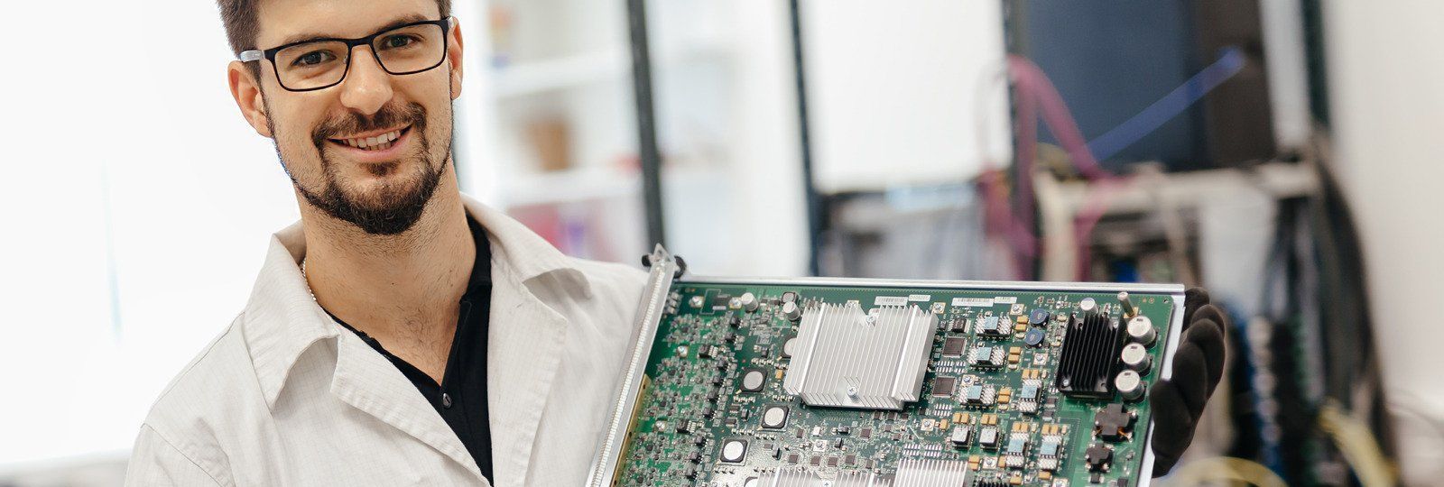 A man in a lab coat is holding a motherboard in his hands