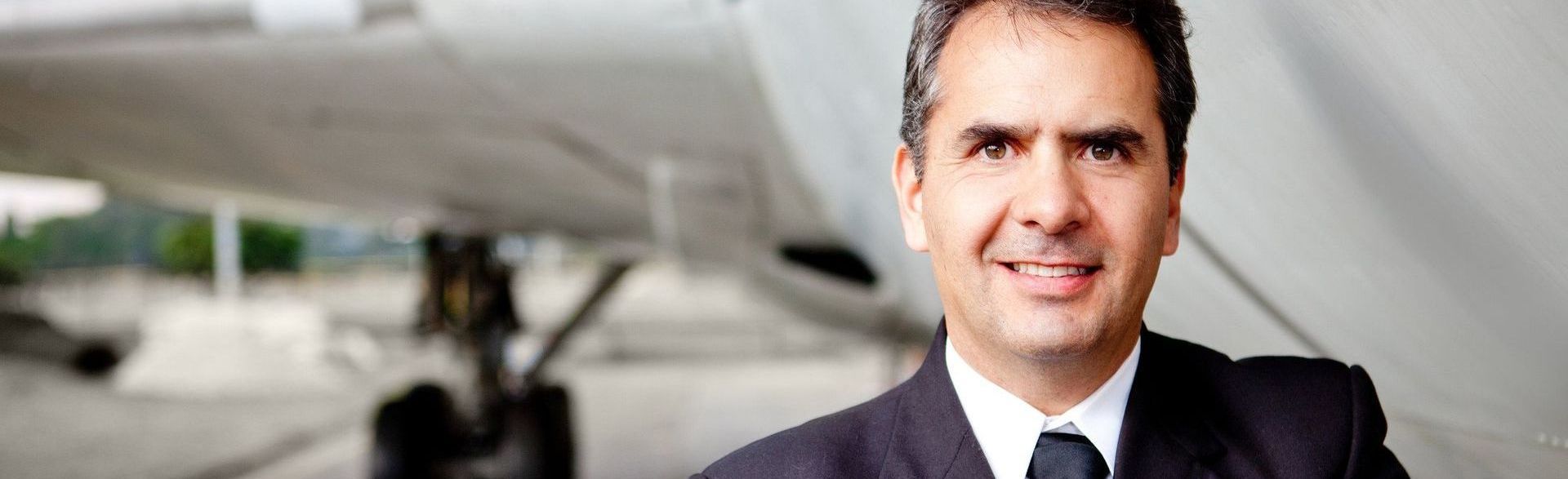 A man in a suit and tie is standing in front of an airplane