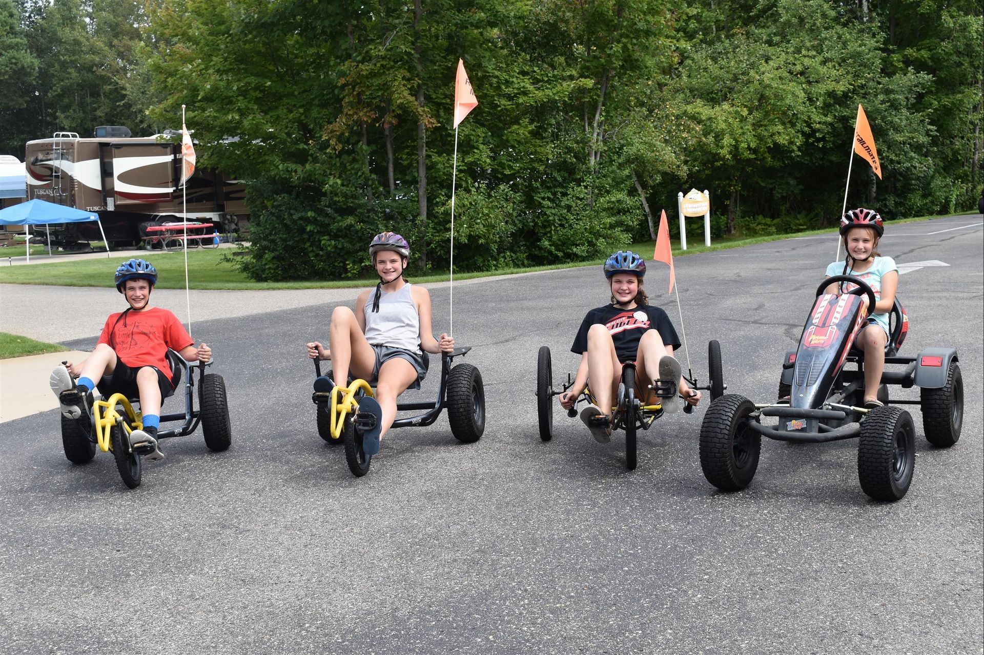 Children smiling and riding pedal bikes.