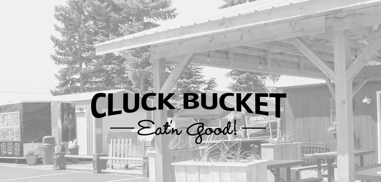A black and white photo of a picnic area with a sign that says cluck bucket eat good.