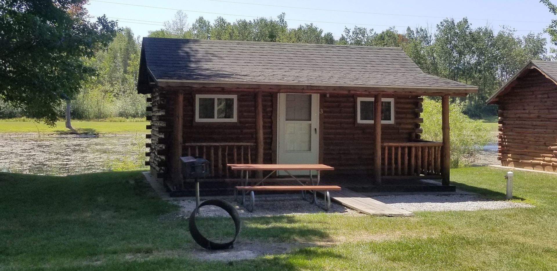 A small log cabin with a picnic table in front of it.