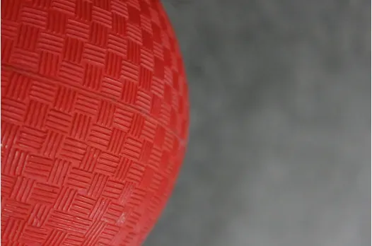 A red ball with a pattern on it is sitting on a gray surface.