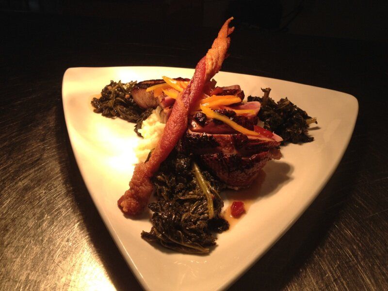 A plate of food with a piece of bacon on top