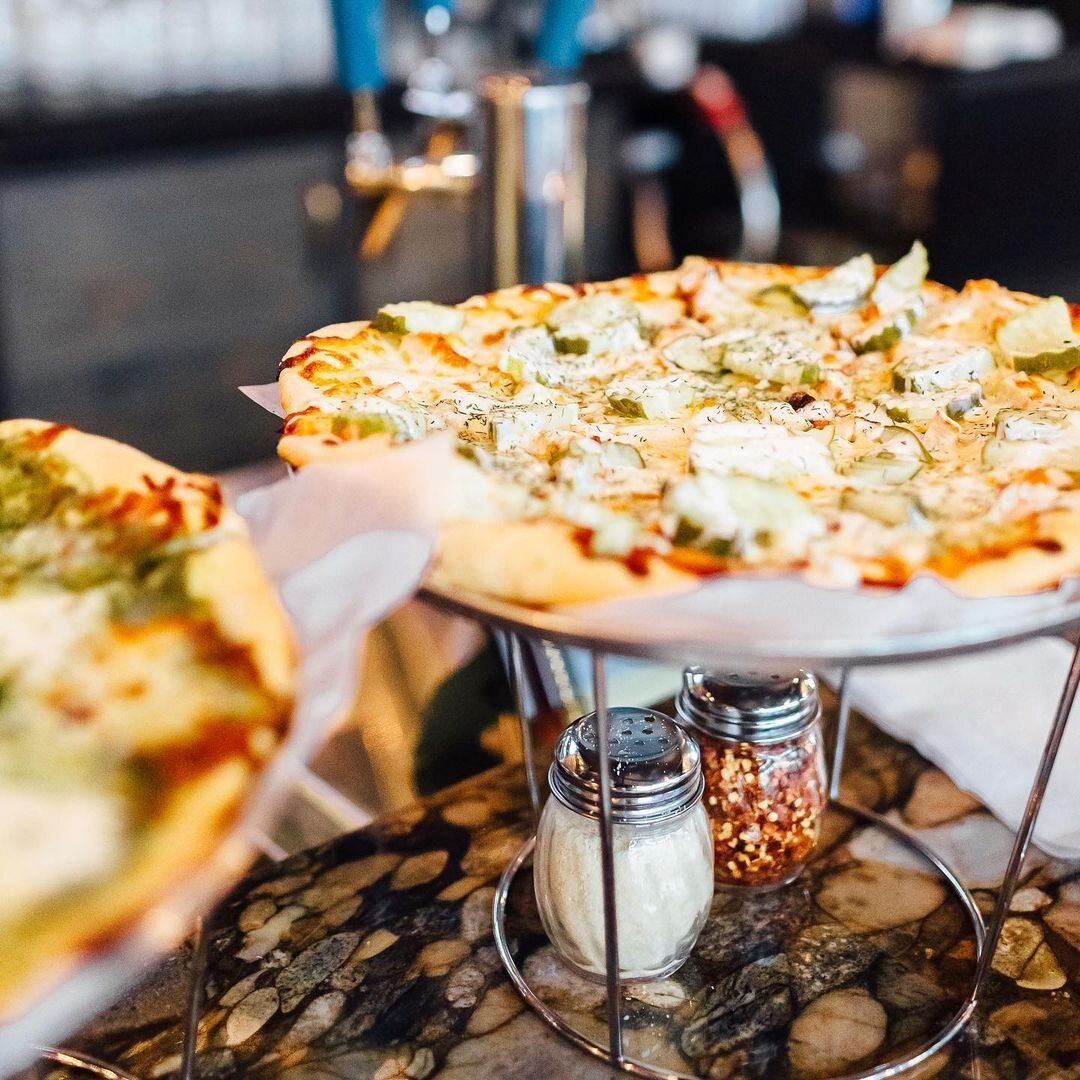 A pizza sitting on top of a table next to salt and pepper shakers