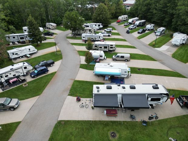 An aerial view of a campground with a lot of rv 's parked on the side of the road.