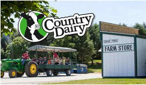 A sign for country dairy shows a tractor pulling a trailer full of people