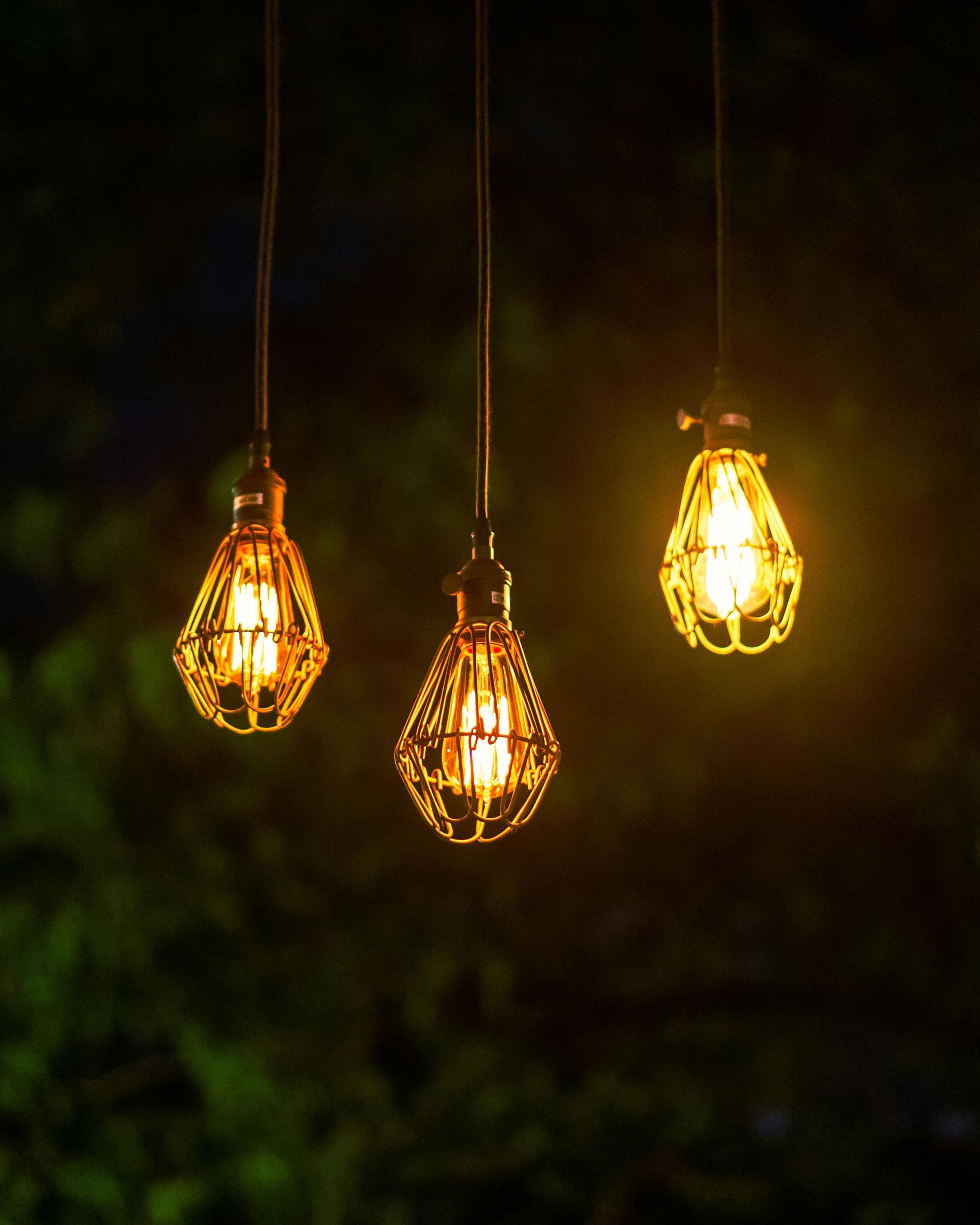 Three glowing hanging light bulbs against a dark background