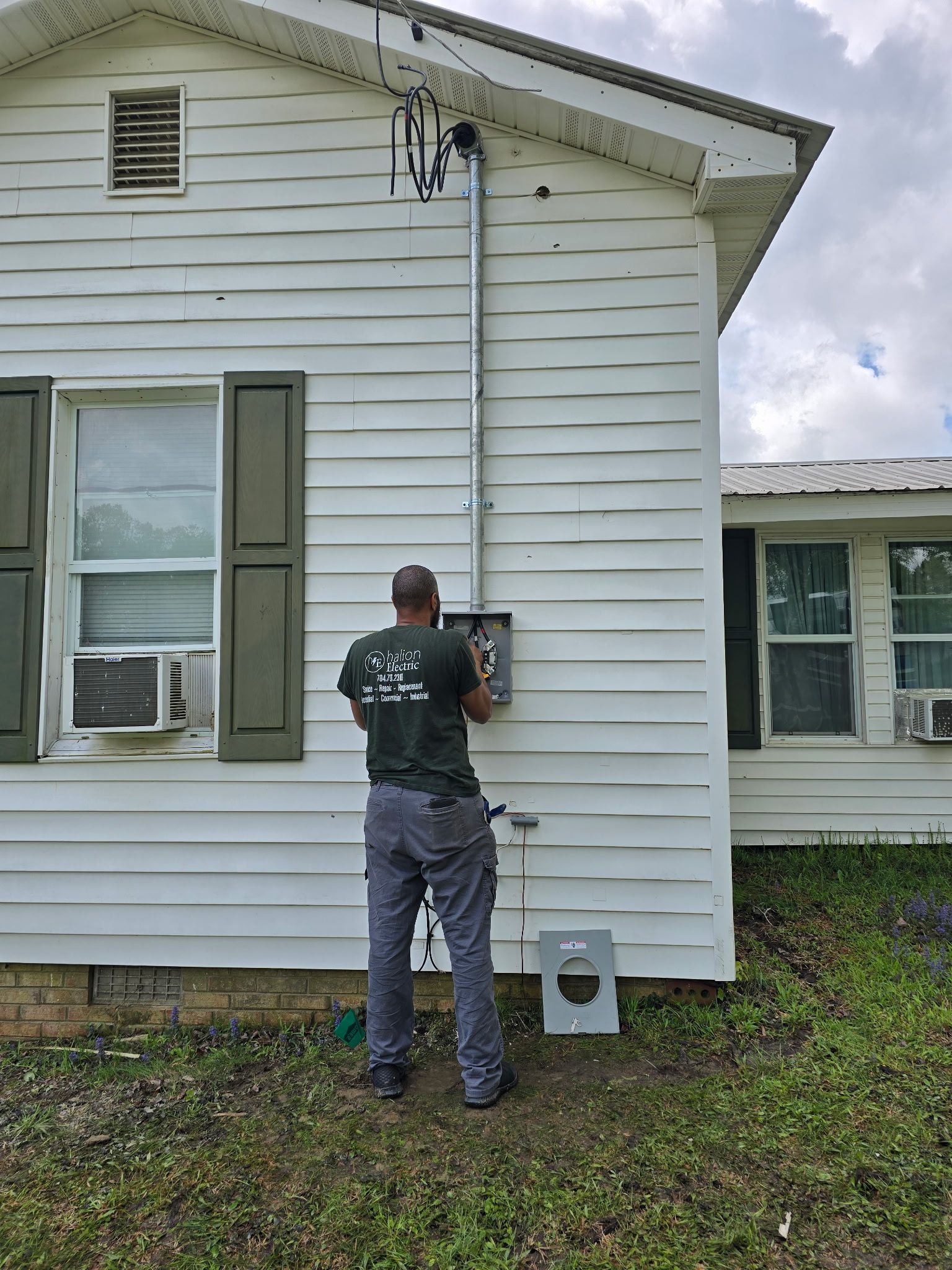 Worker inspecting meter on white house exterior