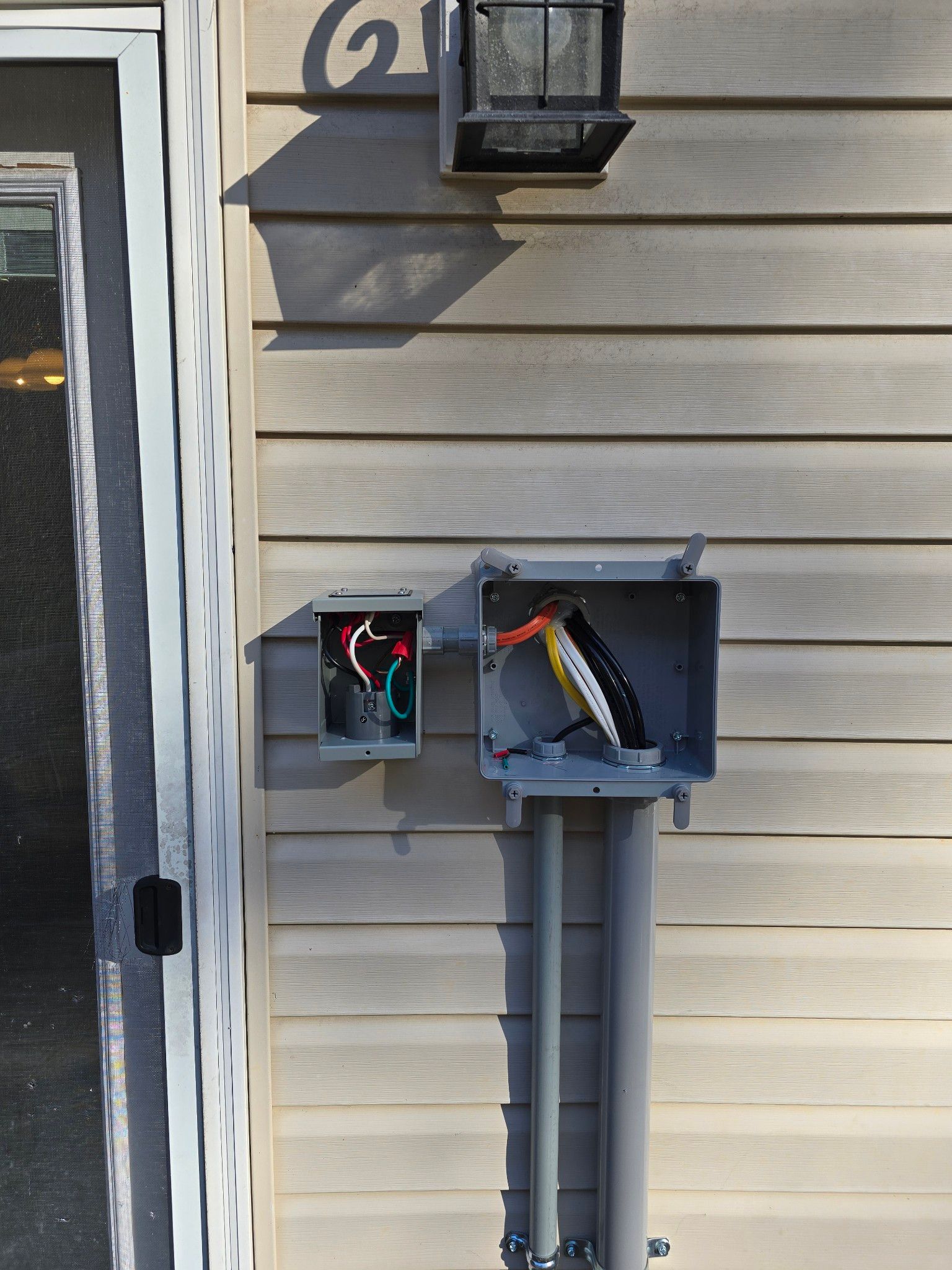 Open electrical meter boxes on a beige house exterior with exposed wiring.