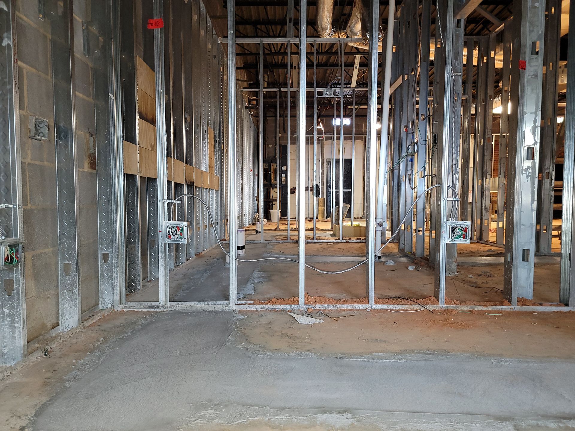 Interior of a construction site with exposed framing, metal studs, and unfinished concrete floor