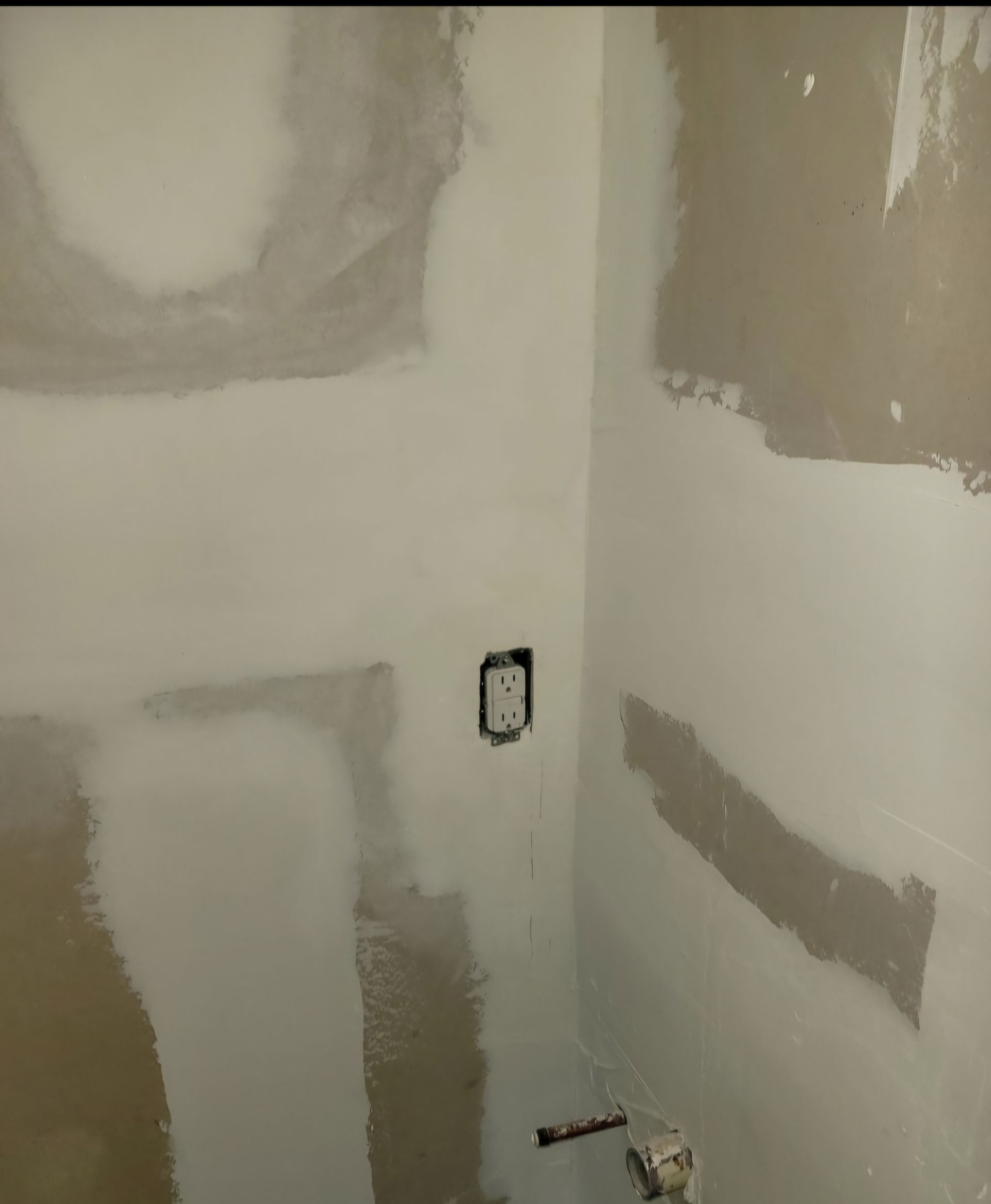 Unfinished drywall corner with patch seams and electrical outlet boxes.