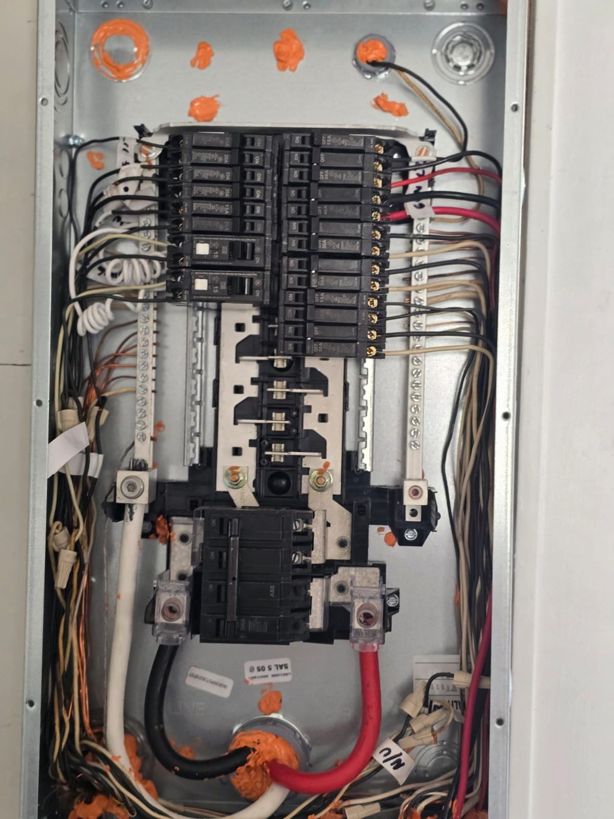 Open electrical breaker panel with rows of black circuit breakers and wiring inside a metal box