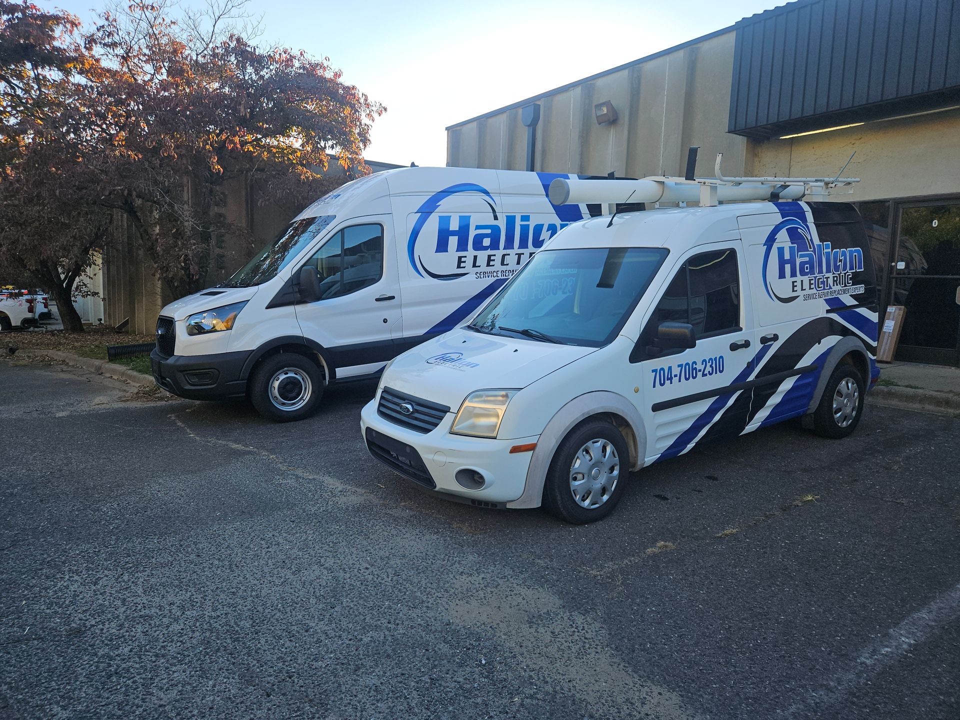 Two white Haila service vans parked outside a building on a gravel lot.