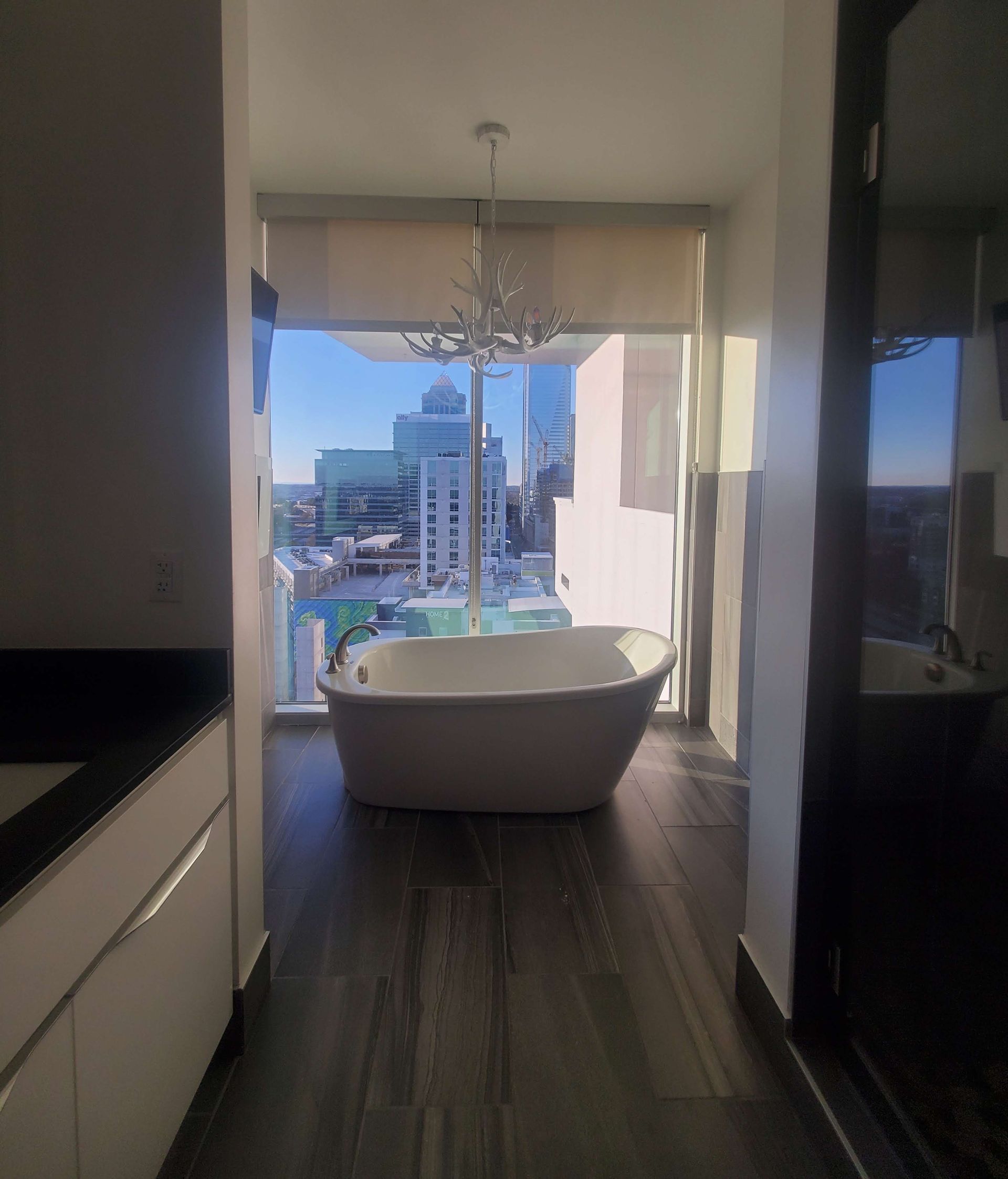 Luxury bathroom with a freestanding tub overlooking a city skyline through large windows.