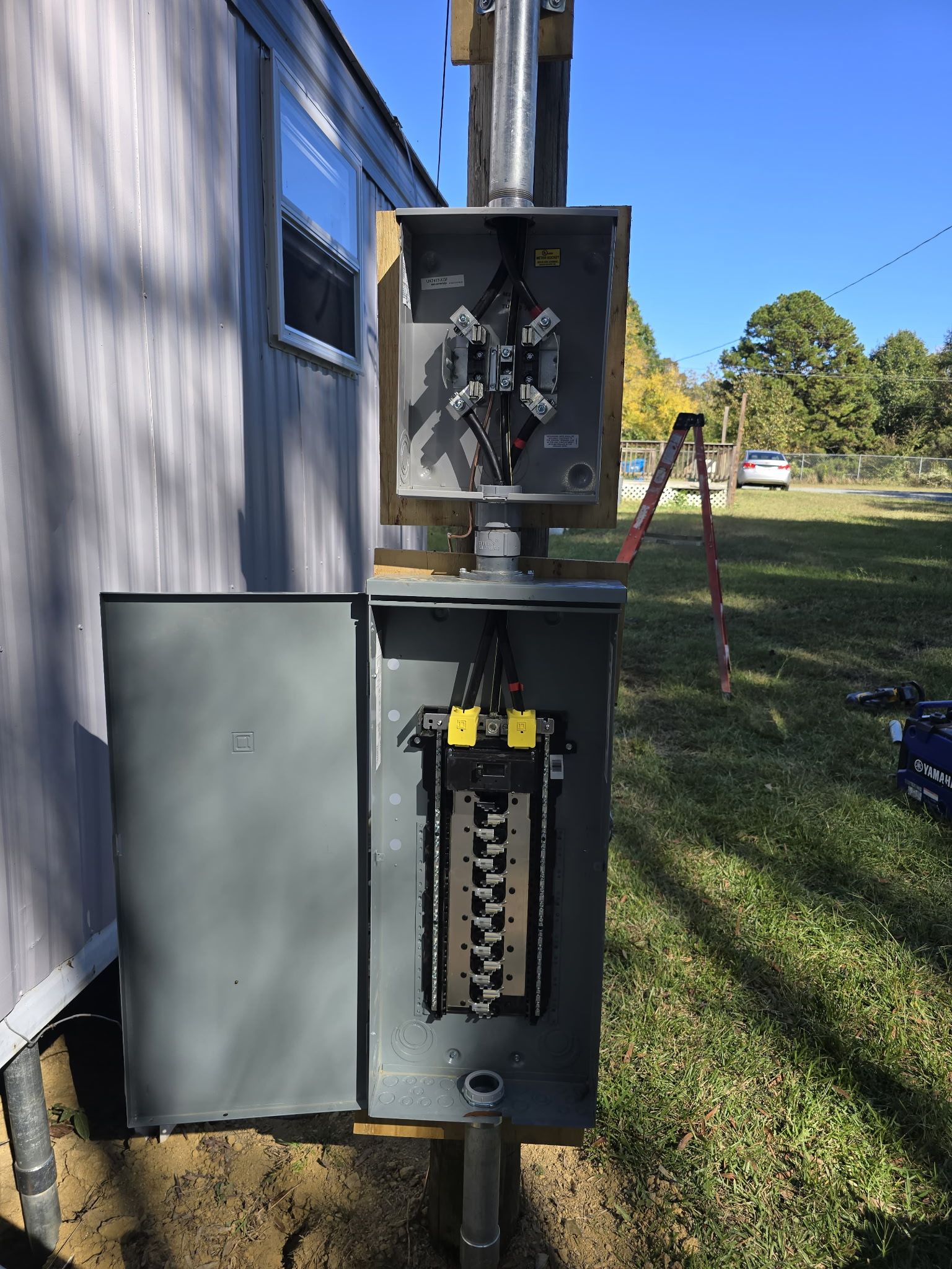 Open electrical panel mounted outside a building with wires and breakers visible.
