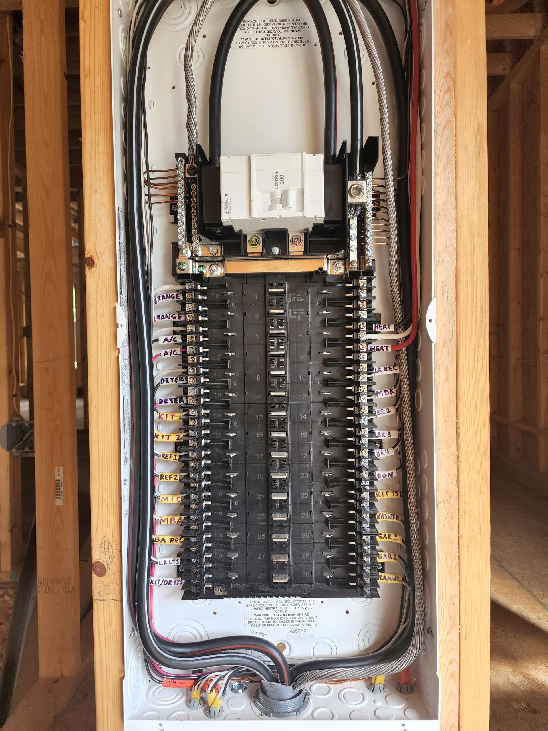 Electrical breaker panel with rows of circuit breakers and wiring inside a wall opening