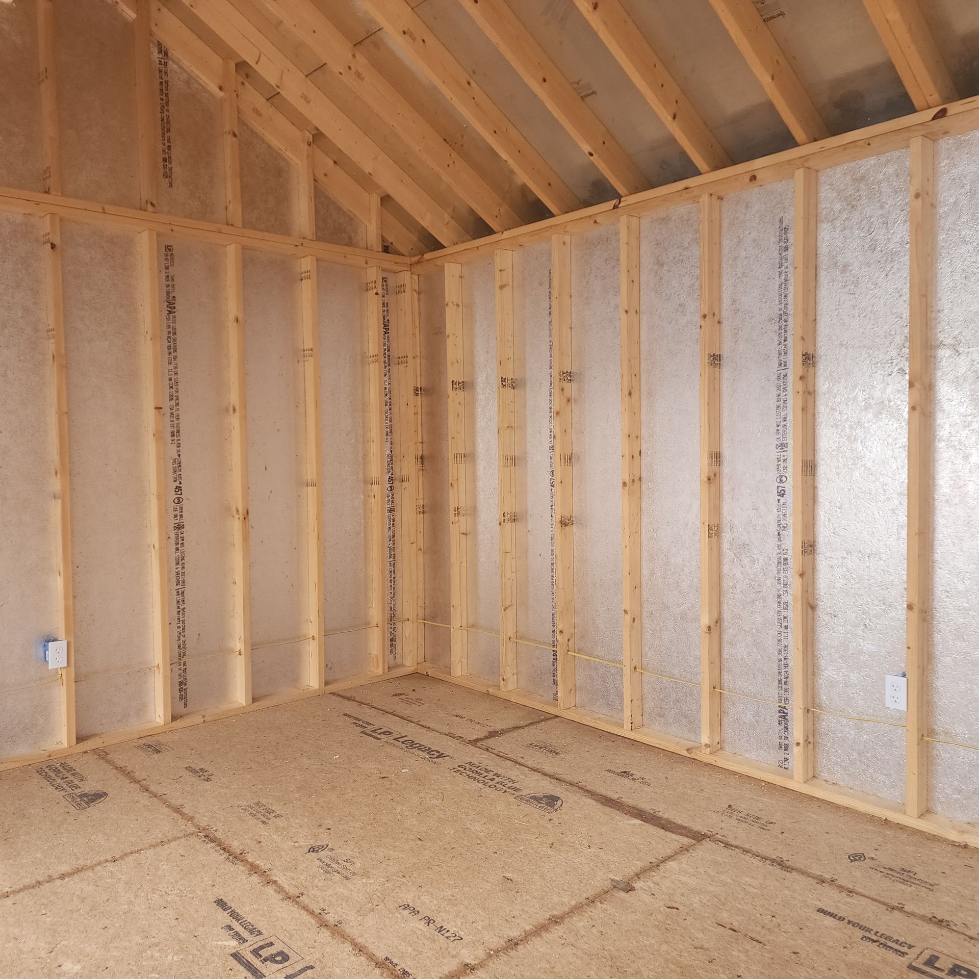 Interior of an unfinished room with exposed wood framing, OSB floor, and insulated walls and ceiling