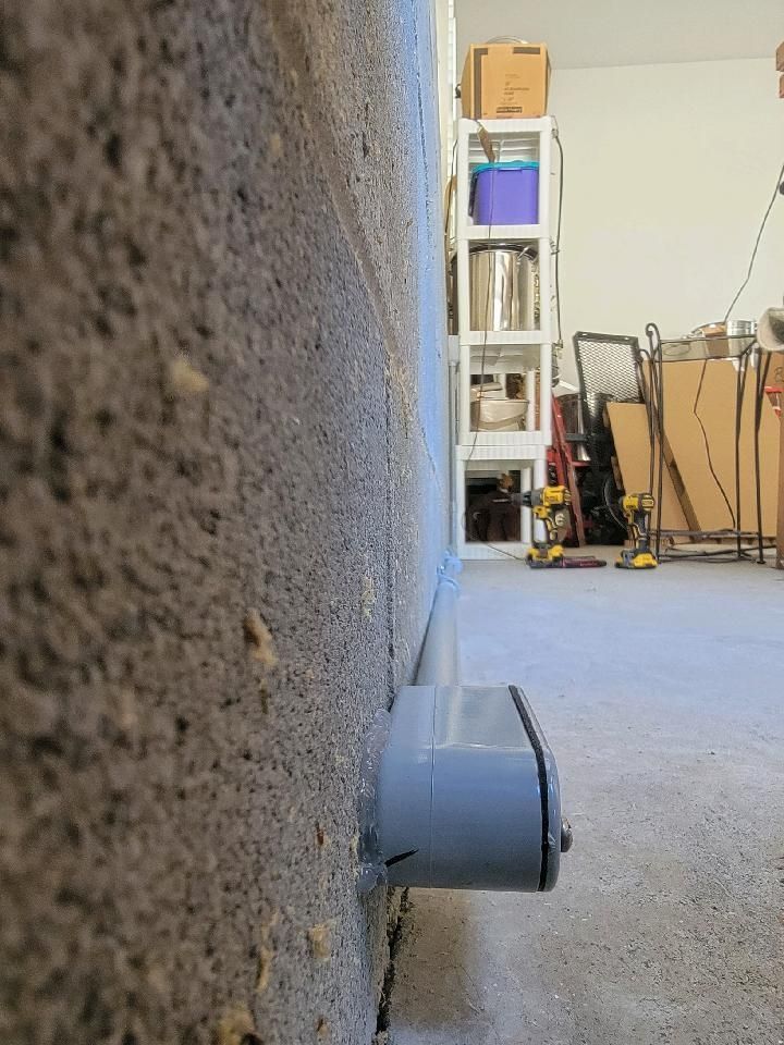 Close-up of a wall outlet with a gray plug in a garage or workshop interior