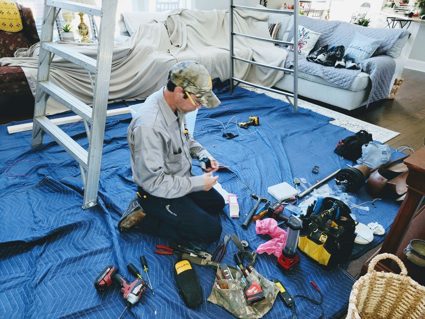 Person kneeling on a blue tarp assembling camping gear inside a tent next to bunk beds