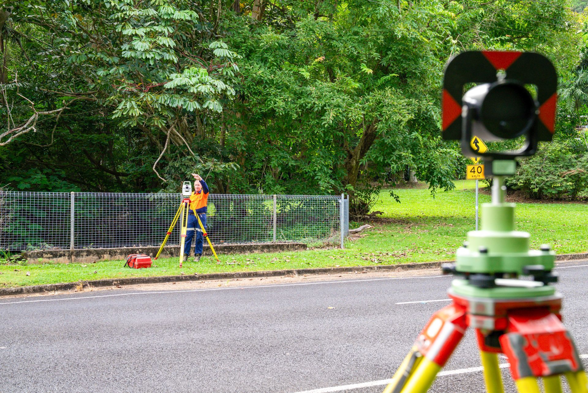 A Man Is Standing Next To A Man Using A Theodolite On A Tripod — TerraModus Surveying In Douglas Shire, QLD