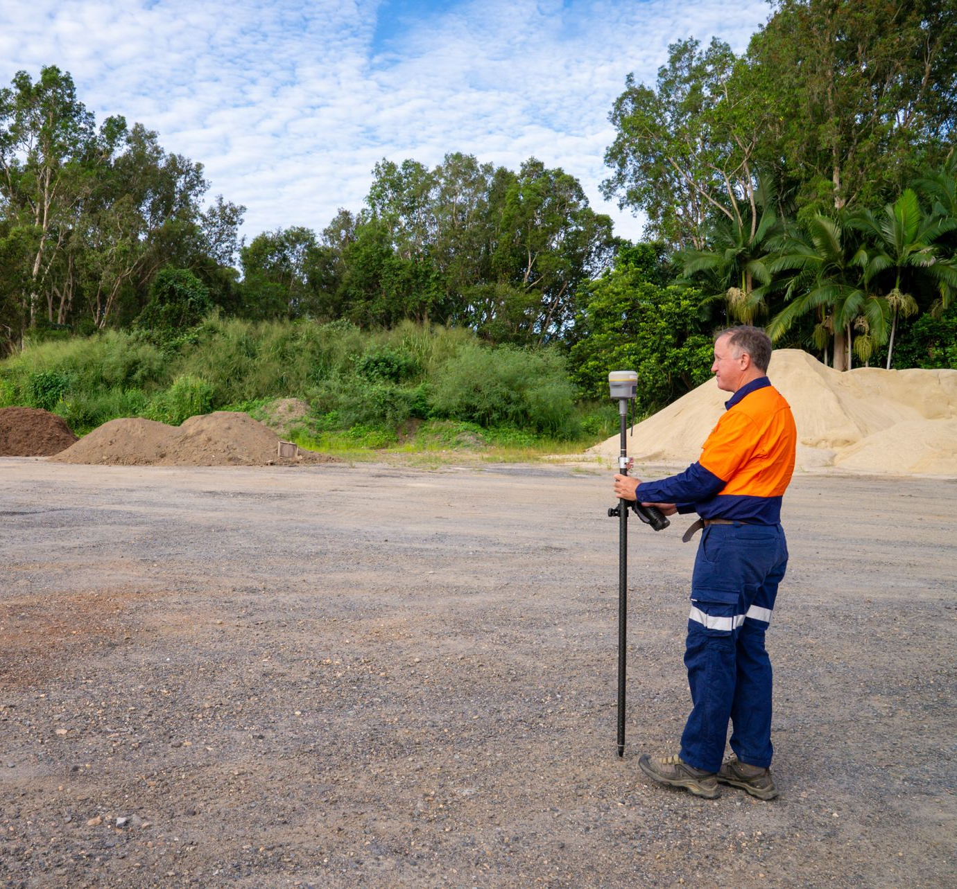A Man Is Standing Next To A Yellow Theodolite On A Tripod — TerraModus Surveying In Cairns, QLD