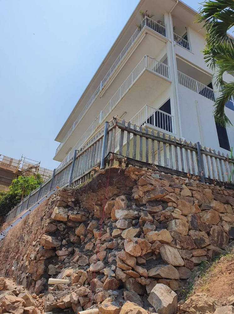 White house with balconies on a rocky hillside under a clear blue sky— High End Stone Masons in West End, QLD